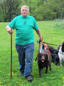 Mike walking three dogs across a grassy field